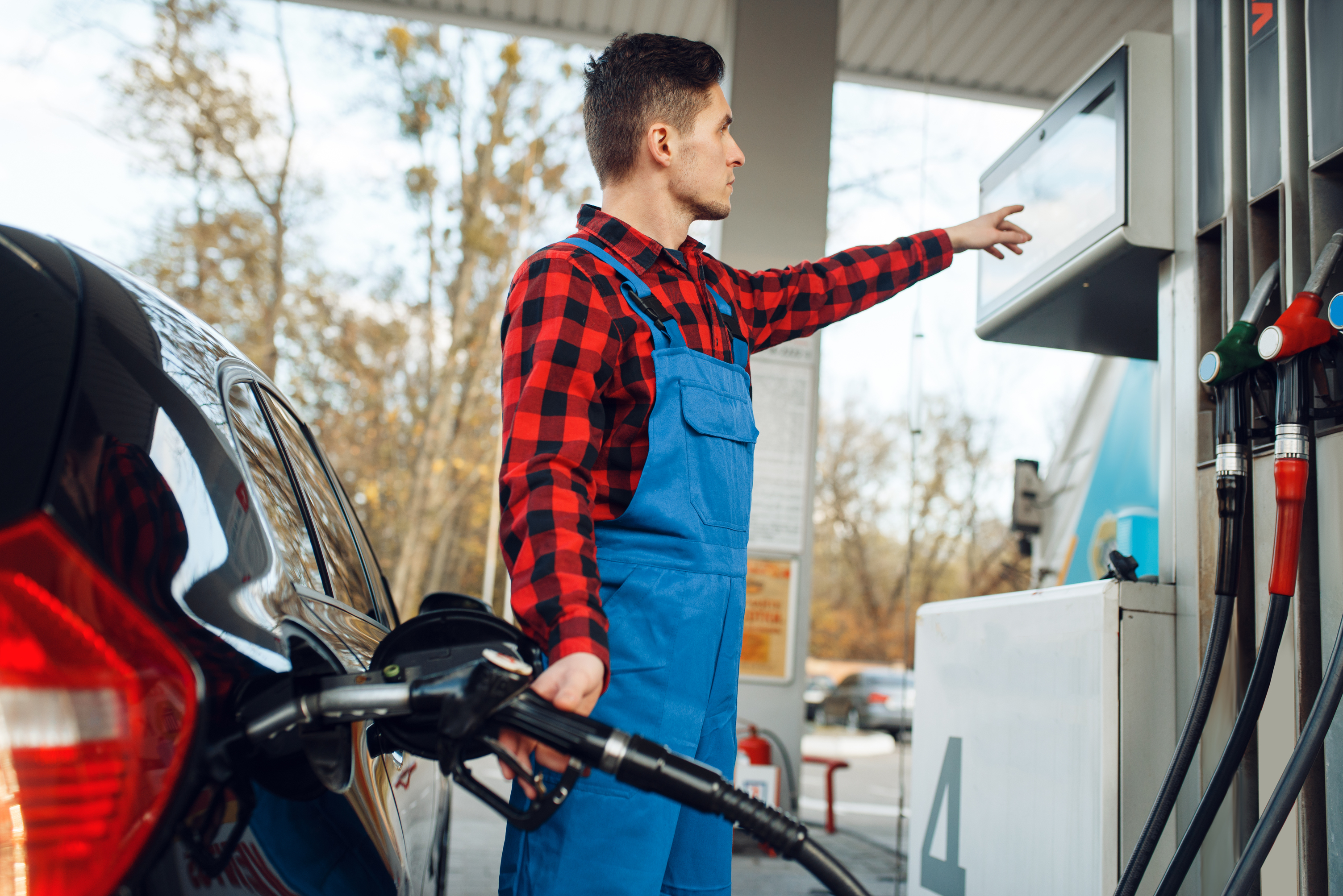 Kde natankovat klvalitní palivo - Mladý muž v monterkách tankuje auto