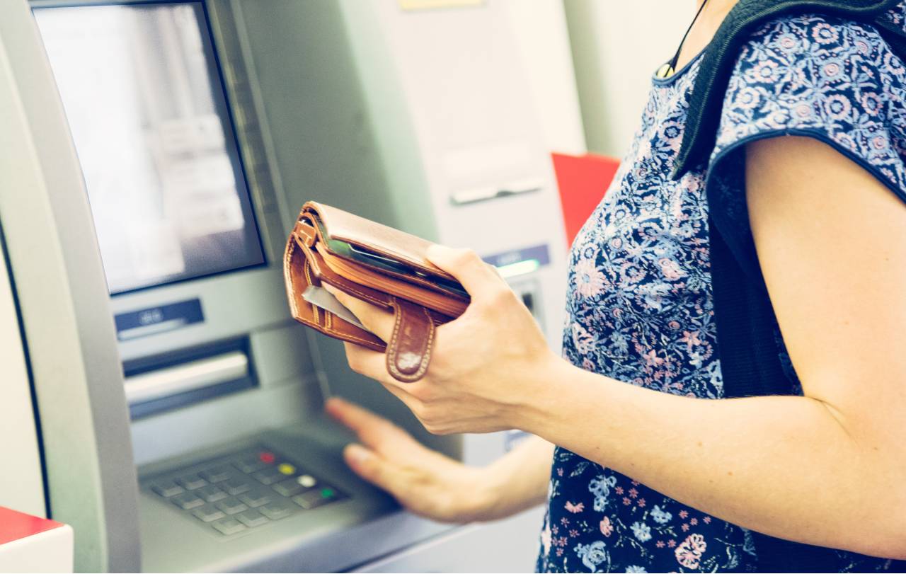 Jak začít šetřit - Žena vybírá z bankomau penze