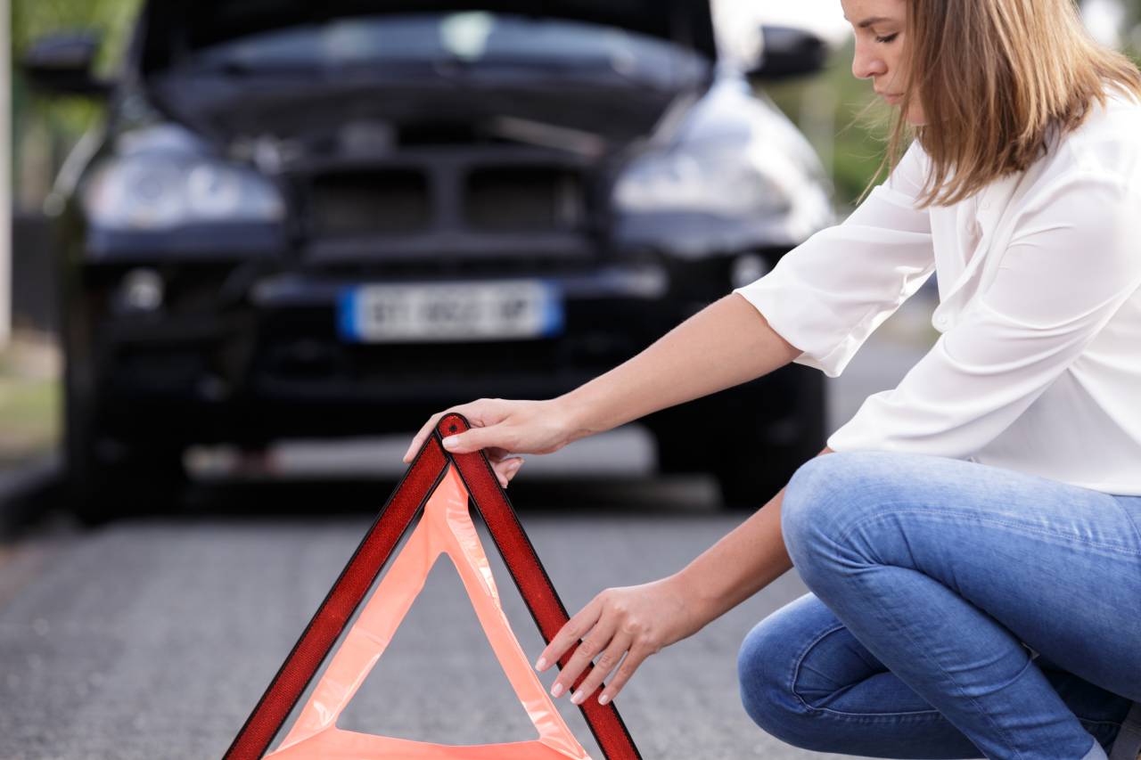 Jaké povinné ručení pro začátečníky - Žena instaluje trojúhelník před auto